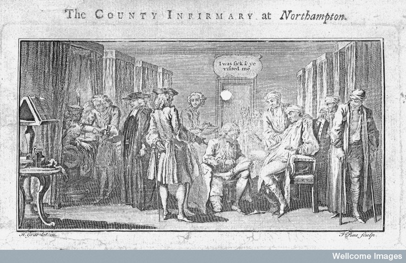 A view of a ward, with curtained beds around the outside of the room.  Patients stand at the edges, and in the centre of the scene a man in a chair is having his leg attended to.