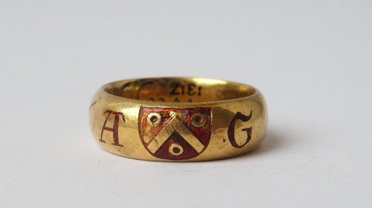 A gold posy ring with inscription - Wee Joyne our harts in god. P over R L. - The exterior is decorated with two red enamelled initials, A and G, and a red enamelled shield