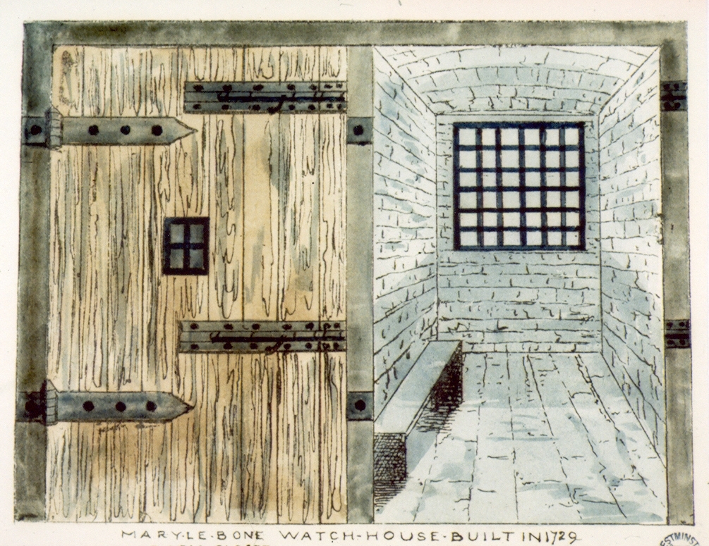 A view into a prison cell with stone built walls and an iron grate over the window